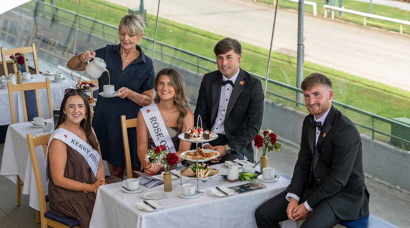 Join the 2026 Roses and reigning Rose of tralee, Katelyn Cummins, for Afternoon Tea with the Roses at the Kingdom Greyhound Stadium on Saturday 15th August Picture shows 2 woman and 2 men dressed well sitting at a table in the Kingdom greyhound Stadium with an afternoon tea setting