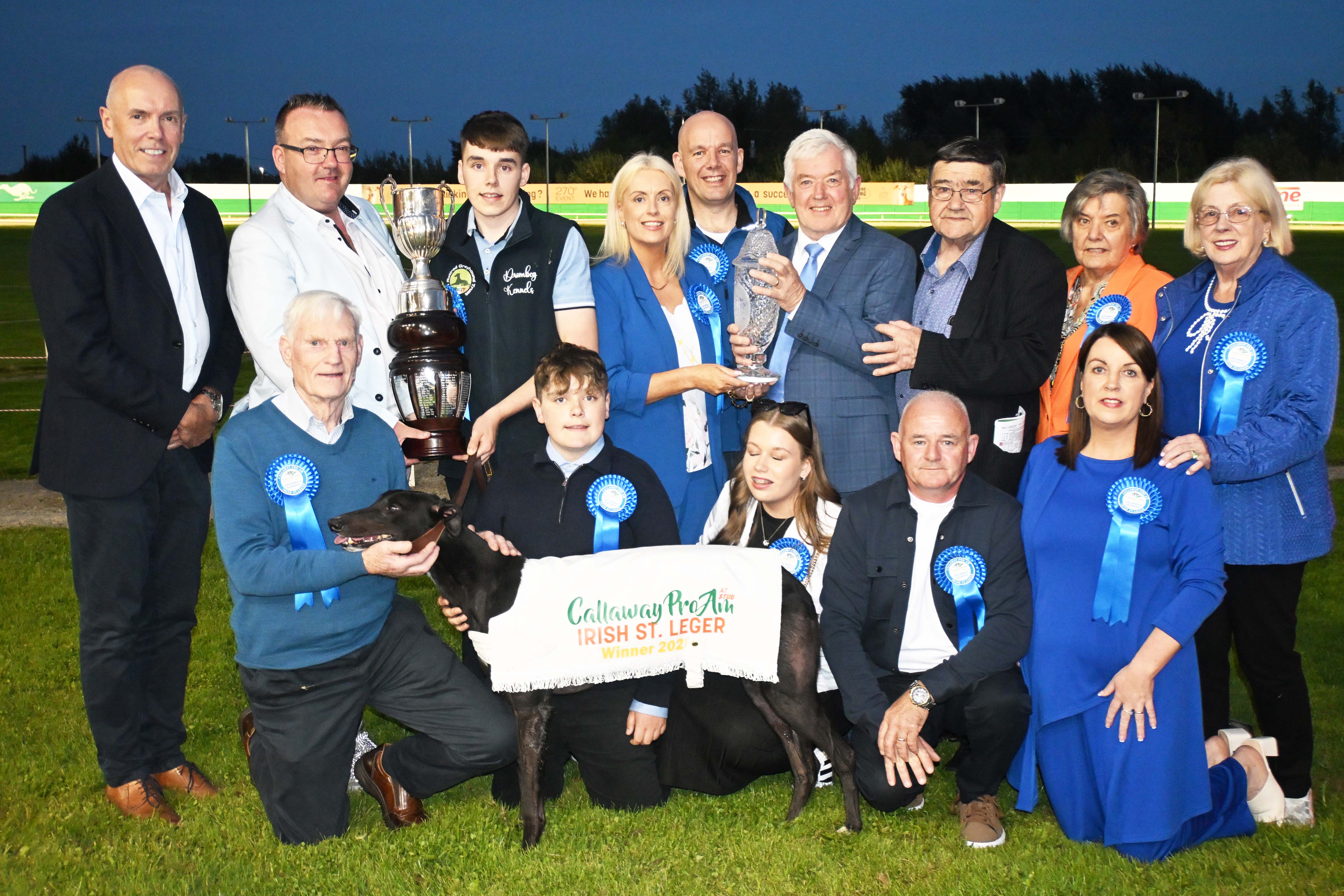 Image shows a group of people and a greyhound at the winner's presentation for the 2025 Callaway Pro Am At Stud Irish St. Leger at Limerick Greyhound Stadium